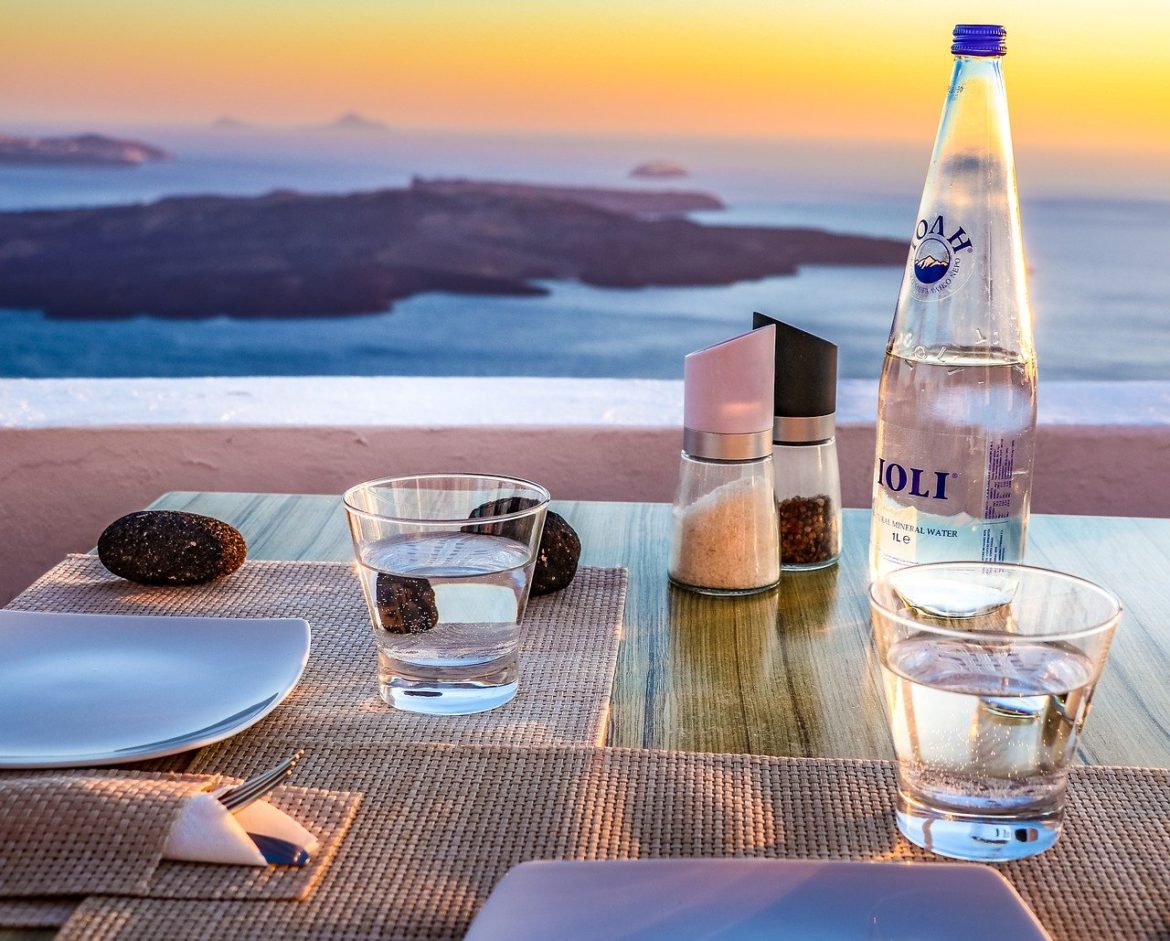 Abendstimmung am Mittelmeer auf der griechischen Insel Santorini. Der Tisch für das Dinner ist schon gedeckt. Ein Glas Wasser gehört immer mit dazu.